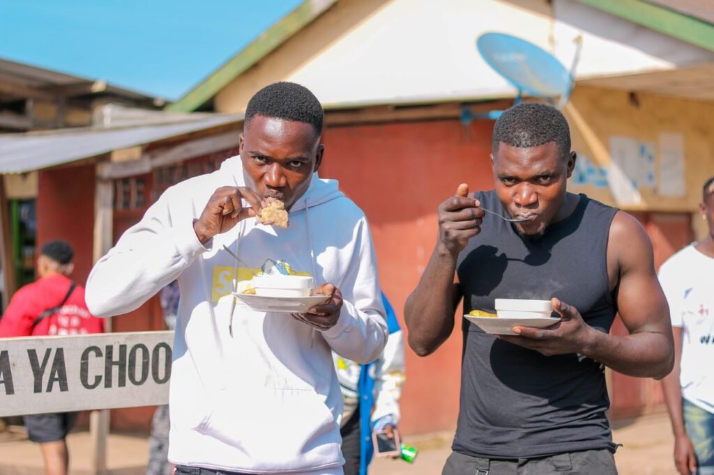 Two men relishing street food outdoors on a sunny day, capturing urban lifestyle.